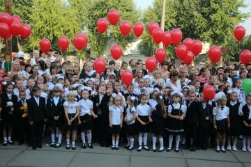 Діти в шкільній формі з червоними кульками на фоні