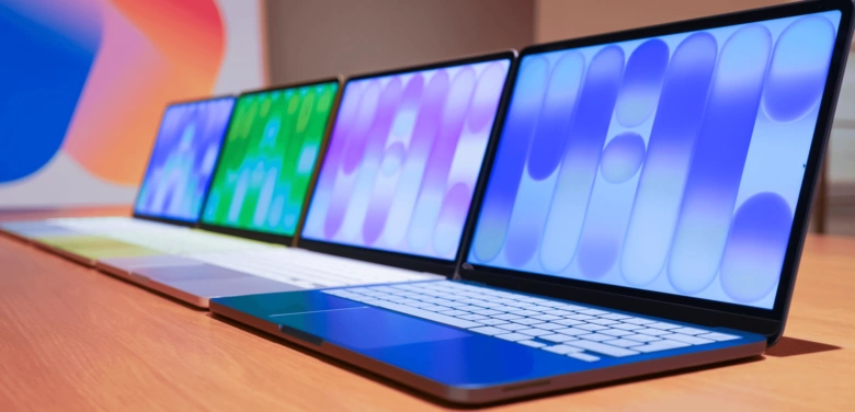 Ряд ноутбуків Apple на дерев'яній поверхні