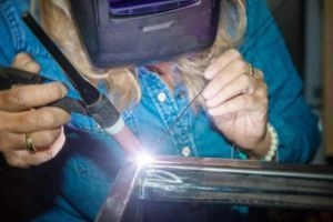 Жінка зварює металеву конструкцію в майстерні