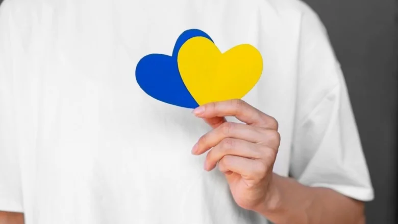 Людина тримає синьо-жовті серця на білому фоні.