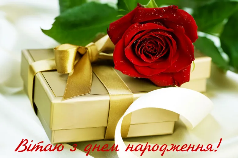 Червона троянда на золотому подарунку з привітанням.