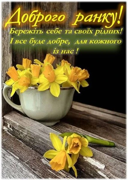 Жовті нарциси в чашці на дерев'яній поверхні з привітанням.